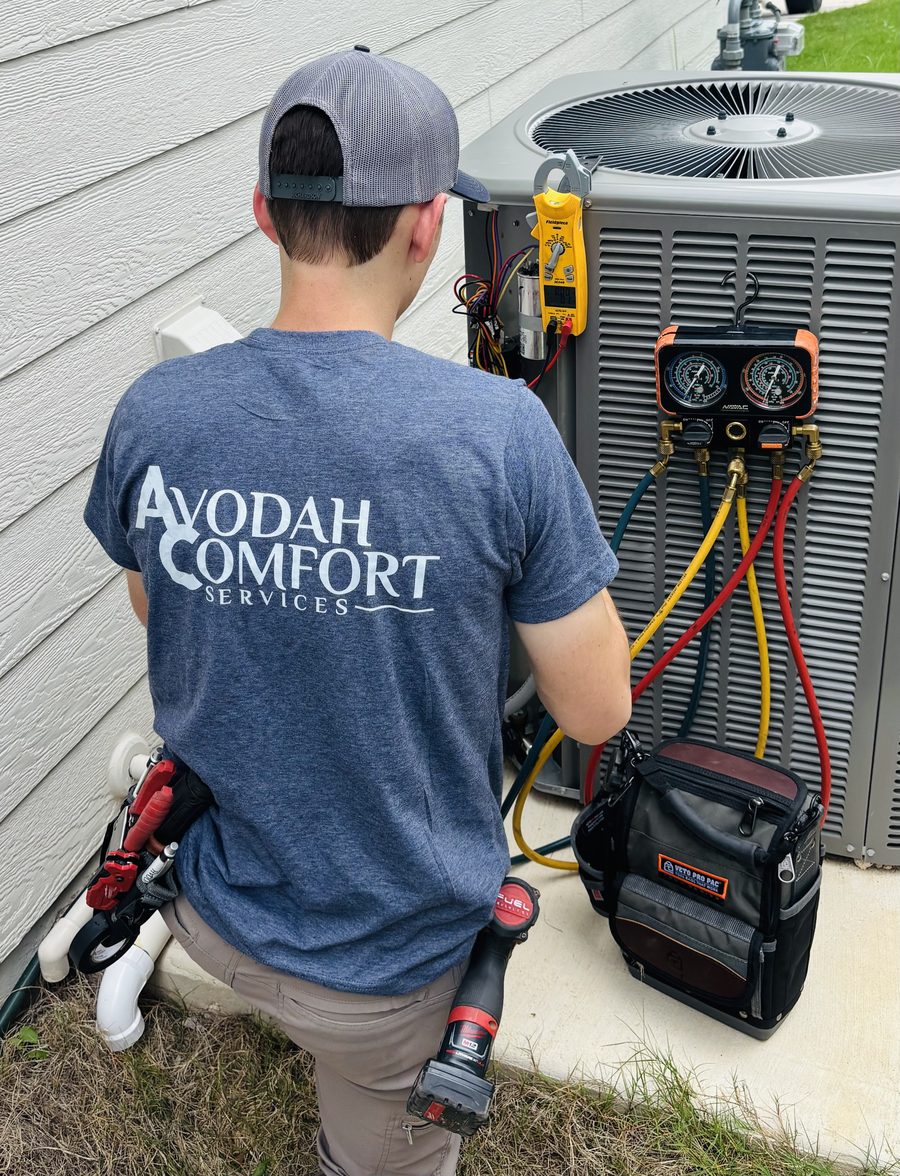 Technician servicing an outdoor air conditioning condenser unit