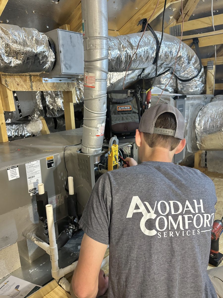Technician servicing a gas furnace and ductwork in an attic